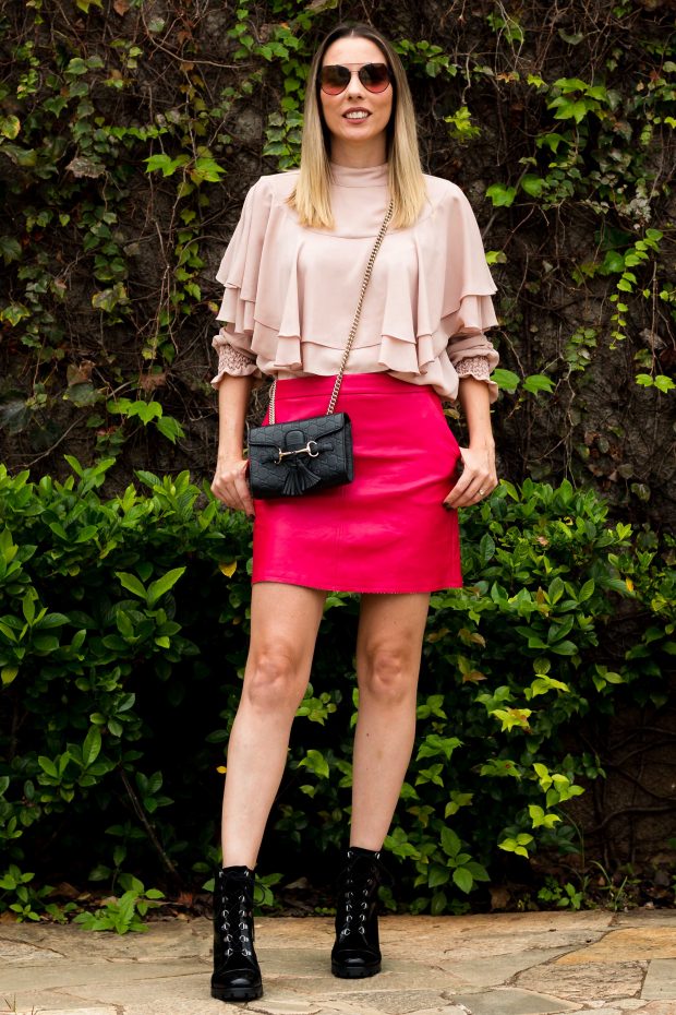 Look de outono da Giuli Castro: saia de couro rosa pink, blusa de babados rosa millennial e coturno.